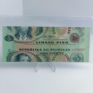 May include: A five peso bill from the Philippines, featuring a portrait of Andres Bonifacio, a Filipino revolutionary leader. The bill is green and brown with intricate designs and the text "LIMANG PISO" and "REPUBLIKA NG PILIPINAS".