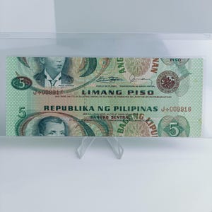 May include: A green and brown Philippine 5 Piso banknote with the text "LIMANG PISO" and "REPUBLIKA NG PILIPINAS" printed on it. The banknote features a portrait of a man in a suit and tie, and a seal of the Bangko Sentral ng Pilipinas.