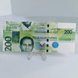 Könnte beinhalten: Ein 200-Peso-Banknote der Philippinen in Grün und Weiß mit dem aufgedruckten Text "DALAWANDAANG PISO" und "REPUBLIKA NG PILIPINAS". Die Banknote zeigt ein Porträt eines Mannes und das Siegel der Philippinen.
