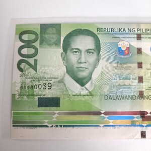 Op de afbeelding: Een groene 200 Filipijnse peso biljet met een portret van een man. De biljet bevat tekst in het Engels en Tagalog, met de woorden "Republika ng Pilipinas" zichtbaar. De biljet is gedateerd 2019.