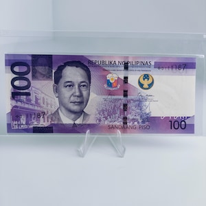 May include: A purple and blue Philippine 100 peso banknote featuring a portrait of a man with the text "REPUBLIKA NG PILIPINAS" and "SANDAANG PISO" printed on it.