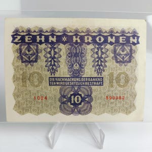 Pode incluir: Uma nota antiga com o texto "ZEHN KRONEN" em azul escuro. A nota apresenta desenhos intrincados, o número "10" várias vezes e o texto "DIE NACHMACHUNG DER BANKNOTEN WIRD GESETZLICH BESTRAFT."