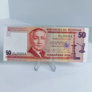 Puede incluir: Un billete de banco filipino de 50 pesos rojo y blanco con el texto "REPUBLIKA NG PILIPINAS" y "LIMAMPUNG PISO" impreso en él. El número de serie "FL205914" está impreso en el billete.