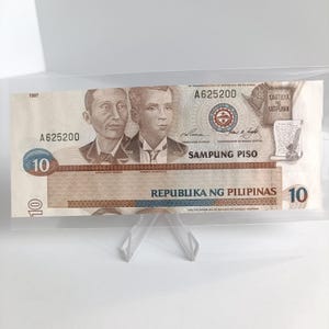 Op de afbeelding: Een vintage Filipijnse bankbiljet van 10 peso met portretten van Apolinario Mabini en Andres Bonifacio. Het biljet is gedateerd 1997 en heeft het serienummer A625200. De tekst "REPUBLIKA NG PILIPINAS" is in blauw gedrukt aan de onderkant van het biljet.