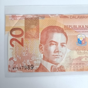 Op de afbeelding: Een Filipijnse bankbiljet van twintig peso met een portret van een man met een vlinderdas. De tekst "Republika Ng Pilipinas" is zichtbaar. Het serienummer is WP547989 en de datum is 2012.