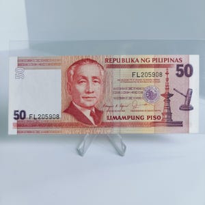 Puede incluir: Un billete de 50 pesos filipinos con el retrato de un hombre con traje rojo y corbata, el texto "REPUBLIKA NG PILIPINAS" y "LIMAMPUNG PISO", y un edificio con un campanario.