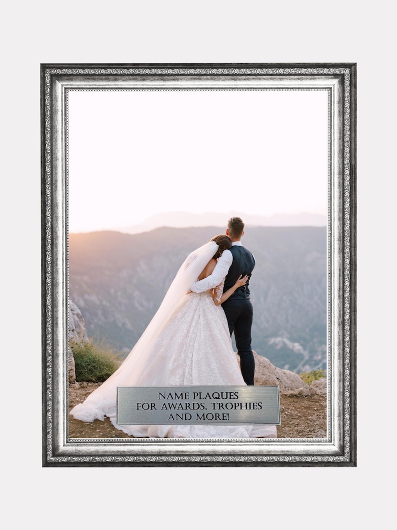 May include: A rectangular silver-toned picture frame with an ornate, textured border. Inside the frame is a photograph of a couple in wedding attire standing on a mountain. A silver plaque at the bottom reads: NAME PLAQUES FOR AWARDS, TROPHIES AND MORE!