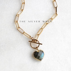 May include: Gold chain necklace with a toggle clasp and a heart-shaped labradorite pendant.