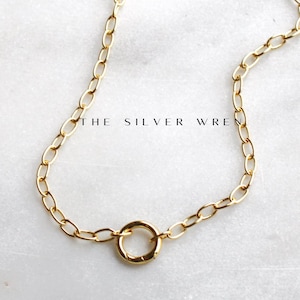 Peut inclure: Un collier en chaîne dorée avec un pendentif rond simple. La chaîne est composée de petits maillons ovales.