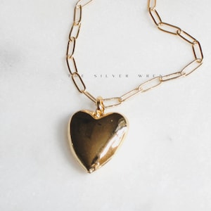 May include: A gold chain necklace with a large, heart-shaped pendant.
