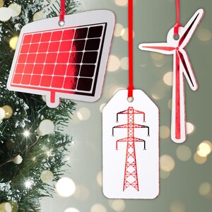 Puede incluir: Adornos navideños blancos y rojos con diseños temáticos de energía. Los adornos incluyen un panel solar, una turbina eólica y una torre de línea eléctrica, todos con detalles rojos y colgados de cintas rojas.