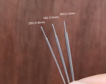 May include: Close-up of three silver piercing needles, labeled 16G (1.2mm), 18G (1.0mm), and 20G (0.8mm). The needles are held against a blurred brown background. The needles are thin and have a sharp point. The image includes the text "@Tinysunny_jewelry".