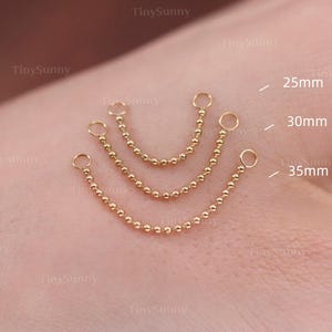May include: Three gold-colored chain earrings with ball beads, each with a different length: 25mm, 30mm, and 35mm. The earrings are displayed on a light skin tone background. The brand name "TinySunny" is visible.