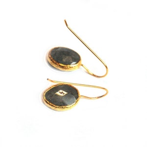 May include: A pair of gold earrings with black oval-shaped stones. The stones have a gold rim and a small diamond-shaped stone in the center.