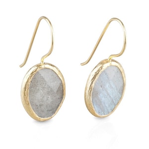 May include: A pair of gold earrings with a round, light gray gemstone set in a gold frame. The earrings have a simple, elegant design.