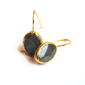 May include: A pair of gold earrings with gray gemstone accents. The earrings have a simple, elegant design.