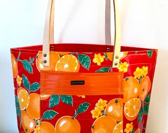 Oranges on red oil cloth tote with leather handles