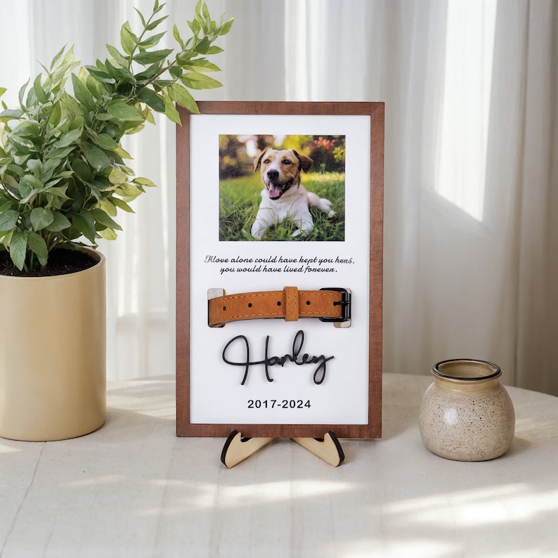 May include: A wooden frame with a photo of a dog, a brown leather collar, and the text "Love alone could have kept you home, you would have lived forever. Harley 2017-2024".