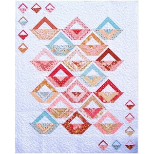 Op de afbeelding: Een quilt met een geometrisch patroon van overlappende driehoeken en vierkanten in tinten roze, rood, bruin en blauw. De quilt is gemaakt met verschillende stoffen met patronen.