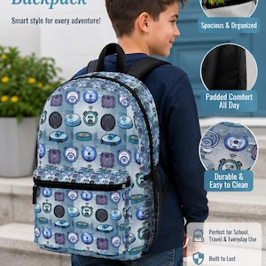 Peut inclure: Un sac à dos bleu avec un motif de robots aspirateurs. Le sac à dos a une poignée supérieure noire, une poche latérale en filet et une poche avant. Le texte sur le sac à dos indique "Robot Vacuum Backpack" et "Smart style for every adventure!"