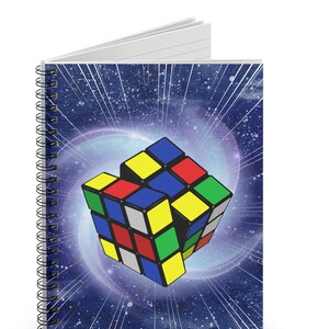May include: A spiral bound notebook with a colorful Rubik's Cube design on a blue and white galaxy background.