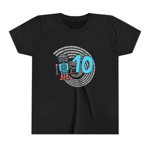 May include: A black short-sleeve t-shirt featuring a graphic print of a small blue and red robot standing next to the large light blue number 10. The design is set against a circular background of white binary code digits arranged in a spiral pattern.