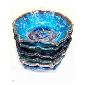 May include: Stack of six blue and brown ceramic bowls with a wavy edge. The bowls are glazed with a blue and brown swirl pattern.