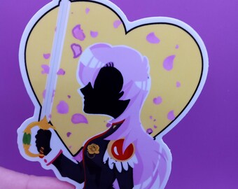 Puede incluir: Una pegatina con la silueta de una persona con el pelo largo de color rosa sosteniendo una espada. La persona lleva un uniforme negro y rojo con un emblema dorado. La pegatina tiene forma de corazón con un fondo amarillo y pétalos de flores rosas.