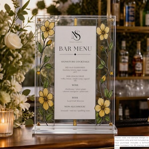 May include: A rectangular clear acrylic bar menu sign featuring a stained glass-style border with yellow flowers and green leaves. The center white panel displays the text NS, BAR MENU, SIGNATURE COCKTAILS, WINE, BEER, and NON-ALCOHOLIC.