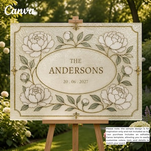 Pode incluir: Uma placa retangular de vidro fosco num cavalete de madeira com borda dourada e centro oval. O design inclui ilustrações de peónias brancas com folhas verdes. O texto diz THE ANDERSONS e a data 20. 06. 2027.