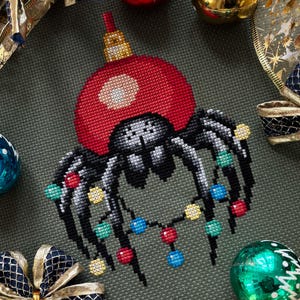 Puede incluir: Una araña negra que lleva un adorno navideño rojo en la cabeza y está rodeada de una cadena de luces navideñas de colores.