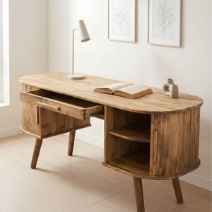 May include: A light brown wooden desk with rounded edges, featuring a single pull-out drawer on the left side and an open storage compartment with a shelf on the right side. The desk is supported by four tapered wooden legs and has a smooth surface.