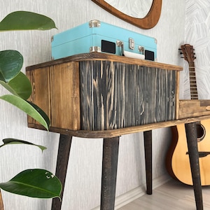 May include: A wooden console table with black stained legs and a light blue vintage record player on top. The table has a rustic, reclaimed wood look and is perfect for a living room or bedroom.