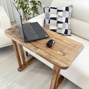 Könnte beinhalten: Ein Laptoptisch aus Holz mit rustikalem braunen Finish. Der Tisch hat eine rechteckige Tischplatte und zwei vertikale Stützen. Ein Laptop und eine drahtlose Maus befinden sich auf dem Tisch.