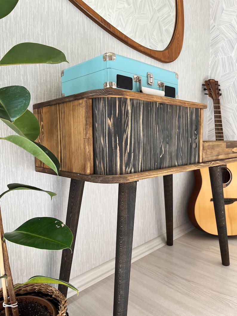 May include: A wooden console table with black stained legs and a light blue vintage record player on top. The table has a rustic, reclaimed wood look and is perfect for a living room or bedroom.