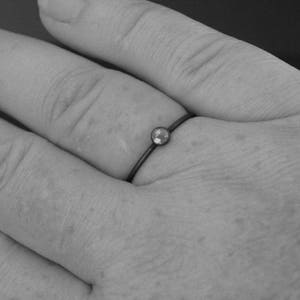 May include: A simple silver ring with a small, clear gemstone set in the center.