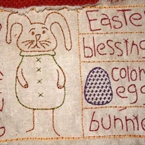 Peut inclure: Un panneau en tissu beige avec des images brod&eacute;es d'un lapin, d'un &oelig;uf et les mots "Printemps", "B&eacute;n&eacute;dictions de P&acirc;ques", "&oelig;ufs color&eacute;s" et "lapins".