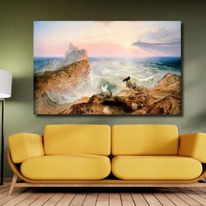 May include: A large framed print of a seascape painting. The artwork depicts a dramatic scene with crashing waves, rocky cliffs, and a vibrant sunset. A black bird and white bird are perched on the rocks. The painting is displayed above a yellow sofa.