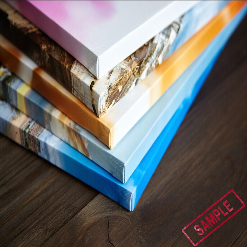 May include: A stack of five canvases with different coloured backgrounds and images. The canvases are stacked on a wooden surface. The top canvas is white with a pink gradient. The second canvas is brown with a white and brown pattern. The third canvas is orange with a white and orange pattern. The fourth canvas is blue with a white and blue pattern. The fifth canvas is light blue with a white and light blue pattern. The word "SAMPLE" is stamped in red on the wooden surface.