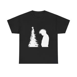 May include: Black t-shirt featuring a white graphic of a Christmas tree and a person in silhouette. The design is simple and minimalist, suitable for casual wear.