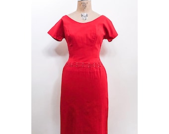 May include: A red sleeveless dress with a fitted bodice and a skirt that falls to the knee. The dress has a unique detail of a row of silver buttons around the waist.
