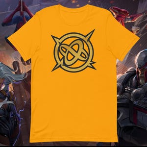 May include: A yellow t-shirt with a gold graphic of a stylized symbol with four points and a circle in the center.