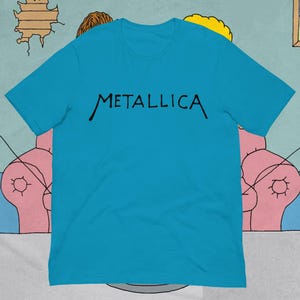 以下が含まれることがあります： 鮮やかなターコイズブルーの半袖Tシャツで、胸の中央に黒い大文字でMETALLICAという文字がプリントされています。このシャツはクルーネックで標準的なフィット感があり、全体が単色でデザインされています。