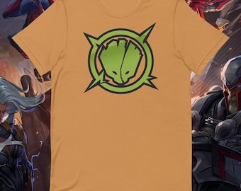 May include: A bright orange t-shirt with a green graphic of a stylized face inside a circle with four points. The graphic is on the front of the shirt.