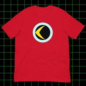 May include: A red t-shirt featuring a circular design with a black center, a yellow crescent, and a light blue outline. The shirt is made of a soft material and has short sleeves.