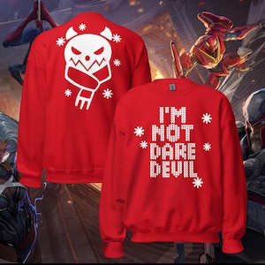 May include: Red sweatshirt with white text and graphics. The front reads "I'M NOT DARE DEVIL" with snowflakes. The back features a white skull design with a scarf and snowflakes. A festive, holiday-themed garment.