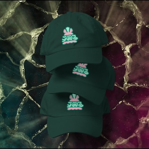 May include: Four dark green baseball caps stacked on top of each other. Each cap has a light green and pink graphic on the front. The caps are displayed against a background of dark purple and gray.