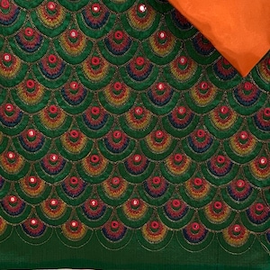 Peut inclure: Tissu vert avec un motif répété de cercles brodés colorés avec des centres en miroir. Le tissu est associé à un tissu orange uni.
