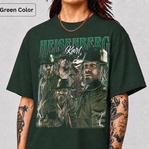 May include: Dark forest green t-shirt with a graphic of a man and the text "HEISENBERG Karl". The design has a vintage aesthetic, with multiple images of the same man. The shirt is a deep green colour.