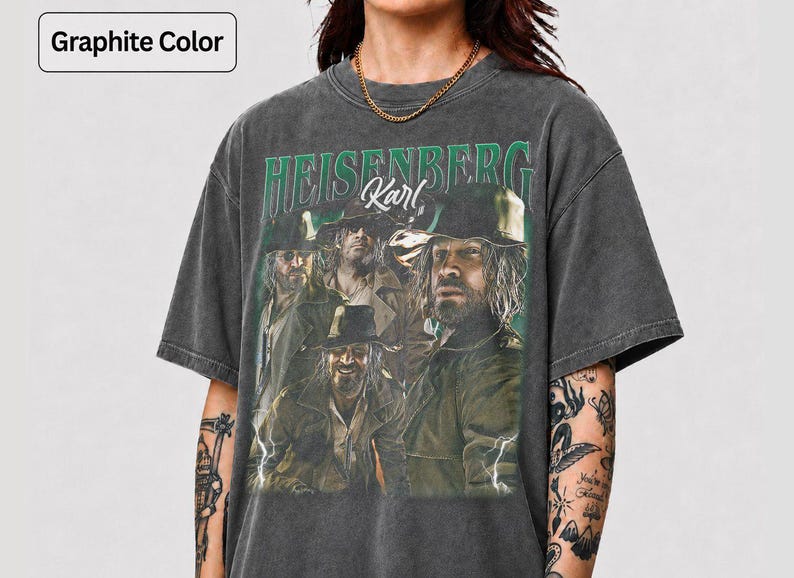 May include: Graphite grey t-shirt with a vintage graphic. The graphic features the text "HEISENBERG Karl" in green, and a group of men in hats and coats. The shirt has a worn appearance.